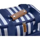 A close-up of a blue and white striped bag with a brown leather handle and a zipper. The fabric has a nautical theme, with a modern design and navy blue straps. The zipper features two leather pull tabs.