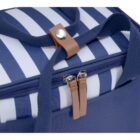 Close-up of a blue and white striped bag with a zipper. The bag has navy blue straps and a brown leather-like buttoned accent on the top.