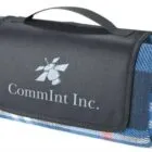 A folded blue plaid blanket with a black flap featuring the CommInt Inc. logo and a carrying handle on top.