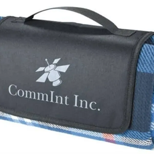 Folded blanket with a blue plaid pattern and a black flap, featuring the logo and text CommInt Inc. on the front. It has a black handle for easy carrying.