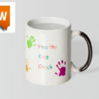 White mug with colorful handprints and text Healthy Kids Check; new label in the corner.