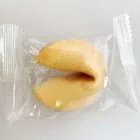 A fortune cookie in a clear plastic wrapper on a white background.