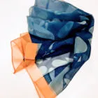 A folded sheer scarf with blue, gray, and orange sections on a white surface.