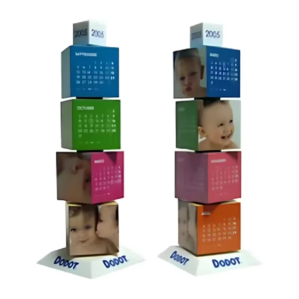 Two Revolving Cube desk calendars for 2005 feature colorful blocks with baby photos and monthly calendars, stacked on sleek white triangular bases labeled DOODT.