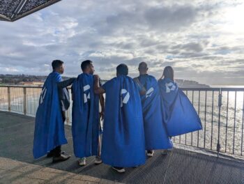 A group posing with their blue capes