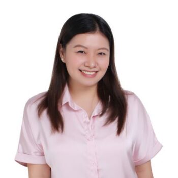 Meet the team: Woman with long dark hair, smiling in a light pink collared shirt on white background.
