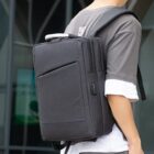 Wearing a Commuter Logo Backpack - rush with front pocket and shoulder straps outdoors.