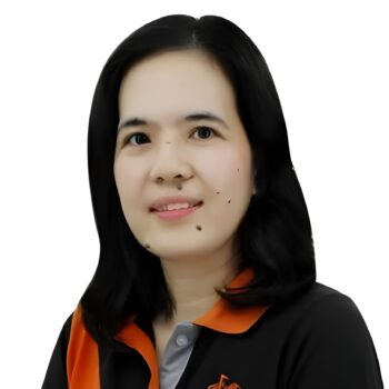 Meet the team: A woman with shoulder-length black hair, smiling in a black and orange collared shirt.