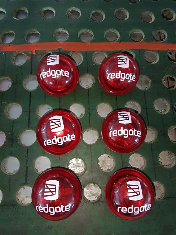 Six red gate-branded red circular objects on a green perforated surface.